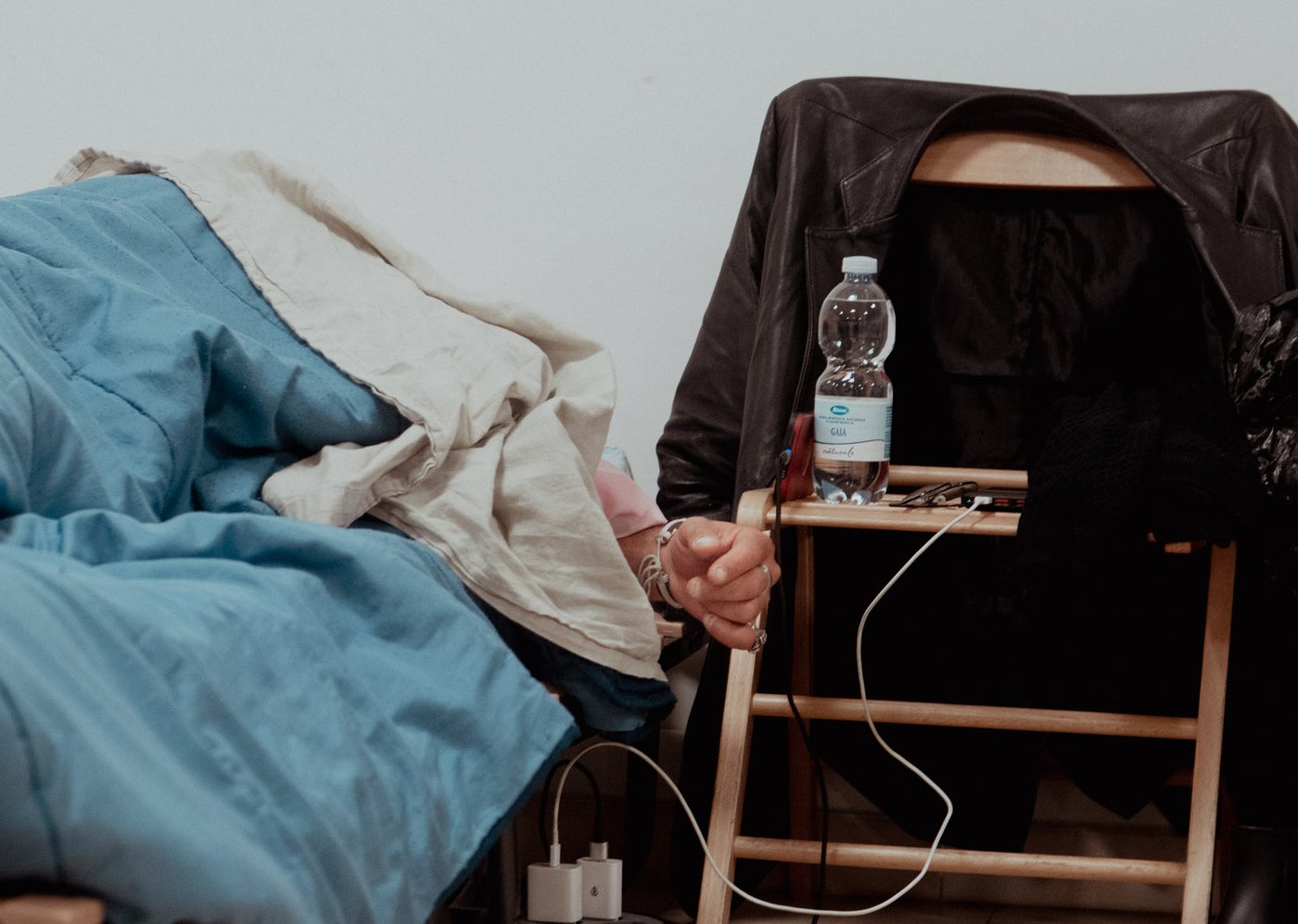 Un letto del dormitorio con una giacca appoggiata alla sedia e un comodino improvvisato