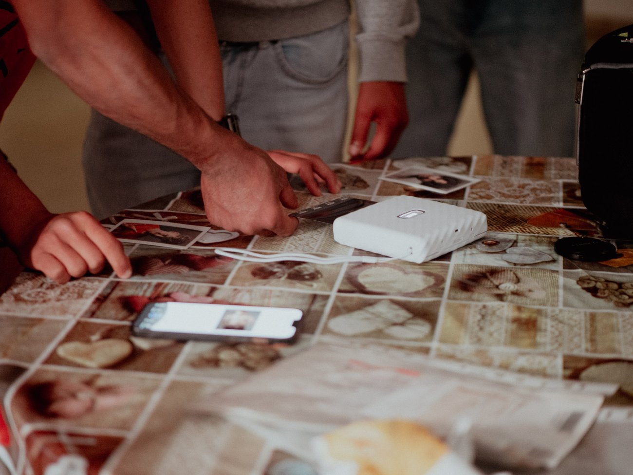 Le Polaroid stampate, sparse su un tavolo, con le mani degli ospiti che le guardano